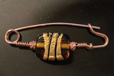 Amber, gold, black, and copper fibula, brooch.