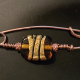 Amber, gold, black, and copper fibula, brooch.