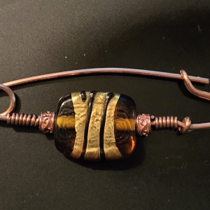 Amber, gold, black, and copper fibula, brooch.